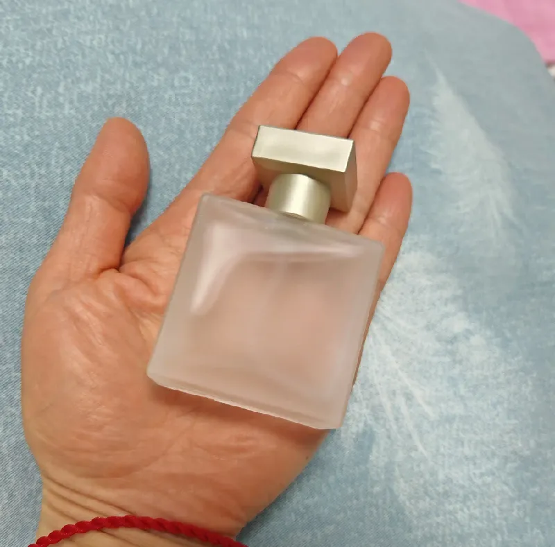 Frascos de perfume de 30 ml, 50 ml y 100 ml en la mano