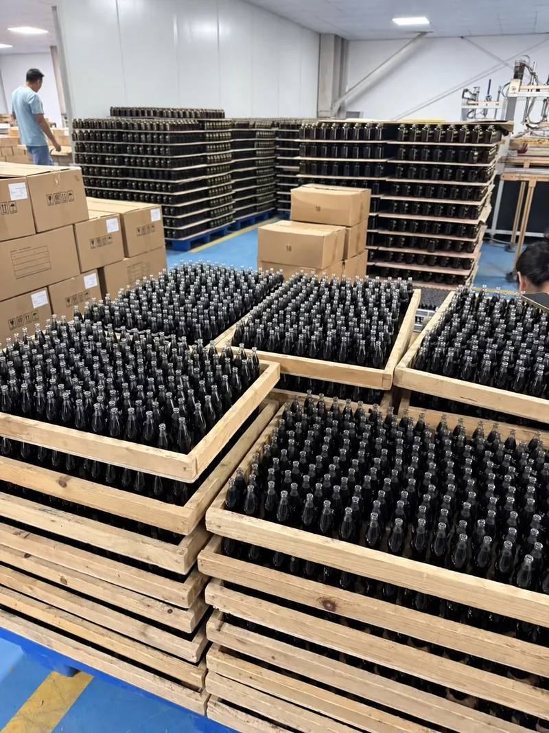 Markenlose Diffusorflaschen aus dunklem Glas, angeordnet in Holzschalen zur Zwischenkontrolle
